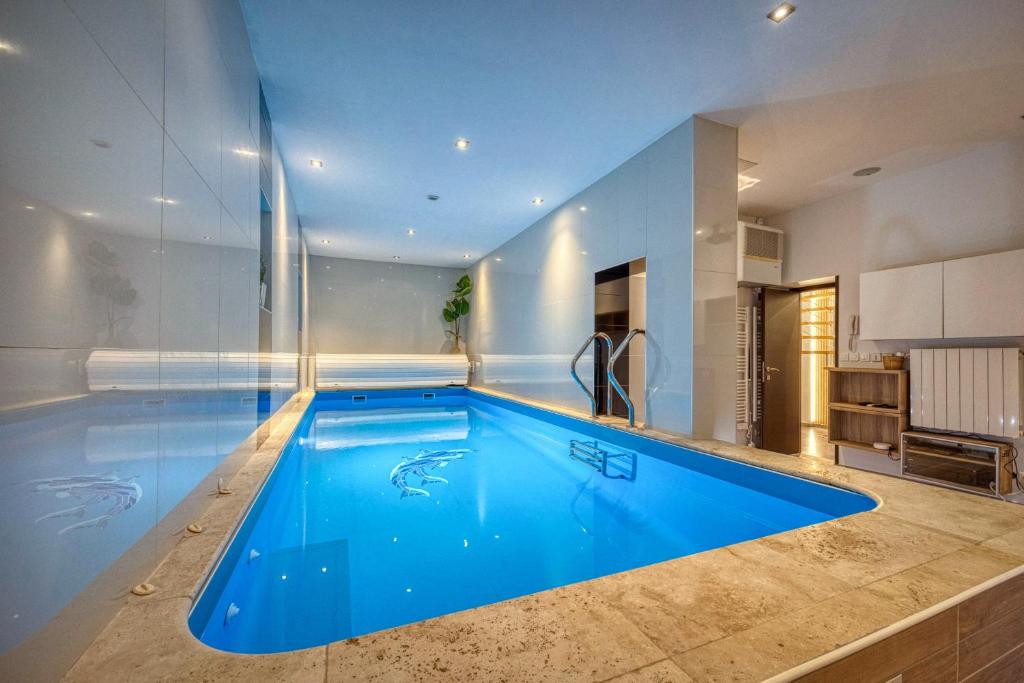 a large blue swimming pool in a room with a kitchen at La Villa - Piscine / Karaoké / Jeux in Fontaine