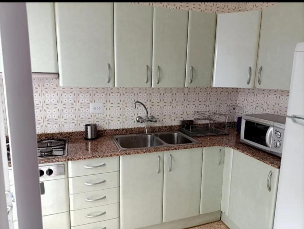 a kitchen with white cabinets and a sink and a microwave at El Molino Buñol Apartamento in Buñol