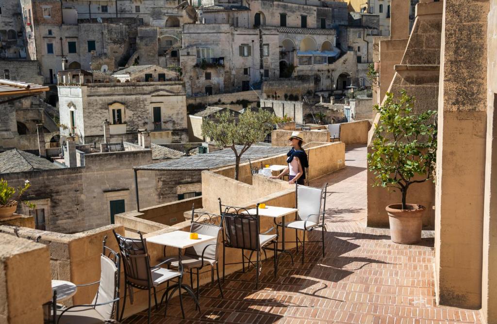 a woman sitting at a table on a balcony overlooking a city at Locanda Di San Martino Hotel & Thermae Romanae in Matera