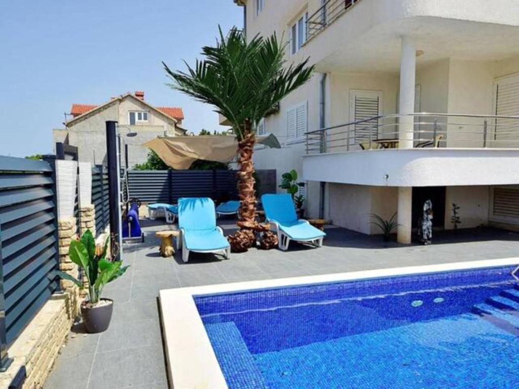 a swimming pool with blue chairs and a house at Nice apartment -with new private pool in Stari Grad