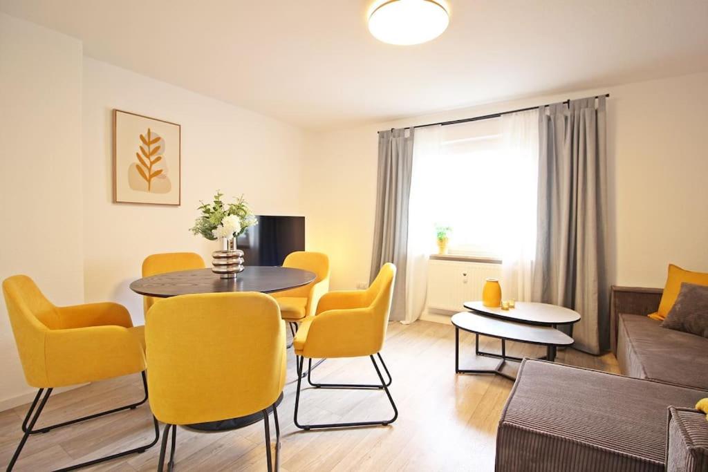 a living room with a table and yellow chairs at Blossfeld-Apartments XL-Ferienwohnung Jena Zentrum, 2 Schlafzimmer, W-Lan, Waschtrockner, Smart-TV in Jena