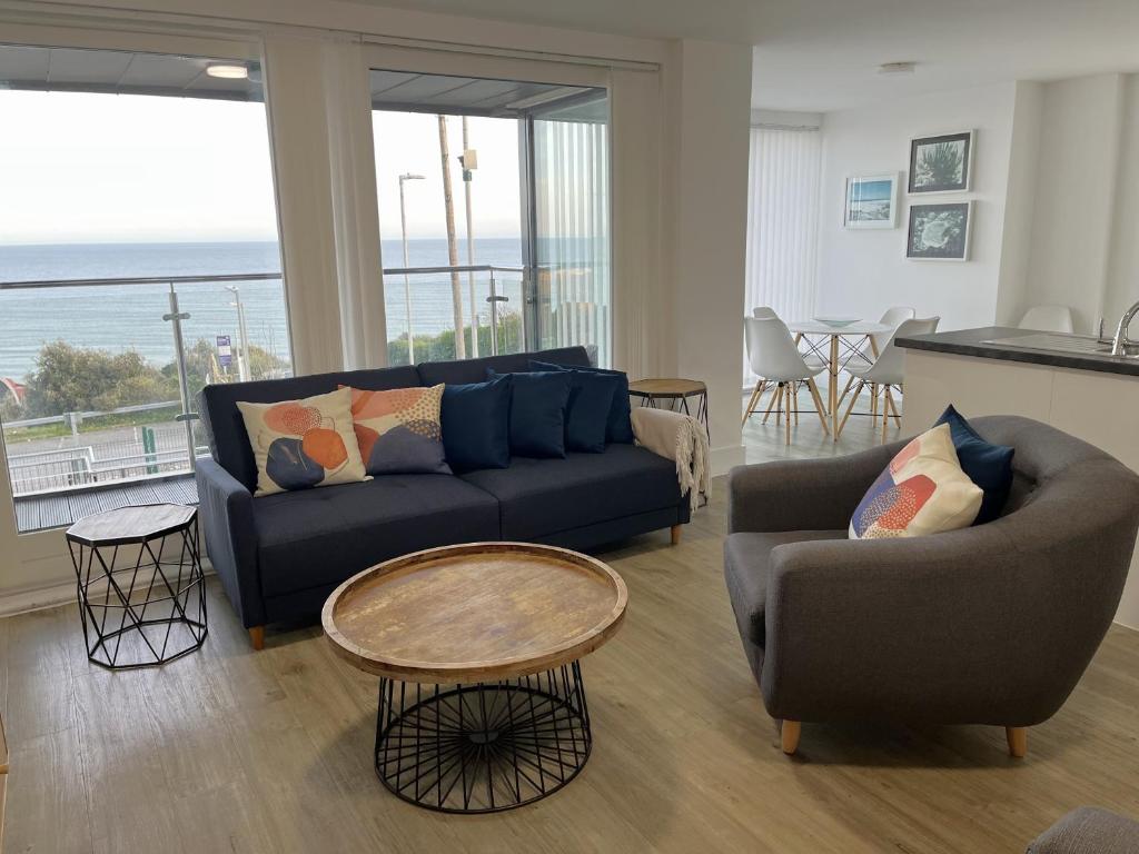 uma sala de estar com um sofá, cadeiras e uma mesa em Seaview West Coast em Bournemouth