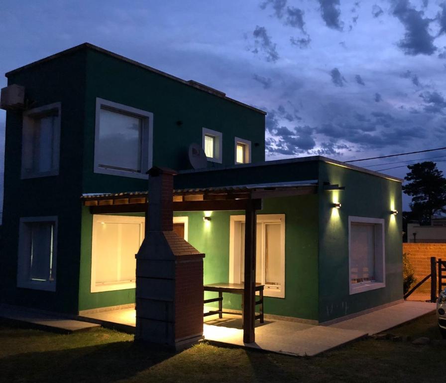 ein grünes Haus mit einem Tisch davor in der Unterkunft Soñada in Tandil