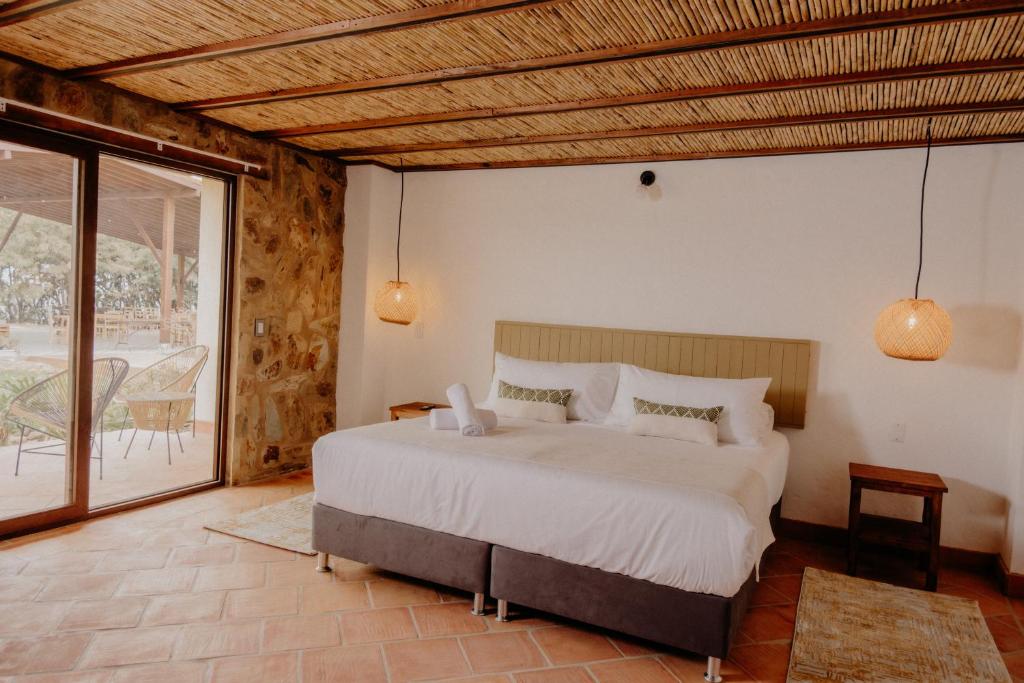 a bedroom with a large bed and a balcony at Pietra Hotel in Sáchica