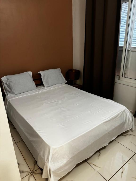 uma cama com lençóis brancos e almofadas num quarto em T3 VILLA DAGONI LOGONI em Koungou