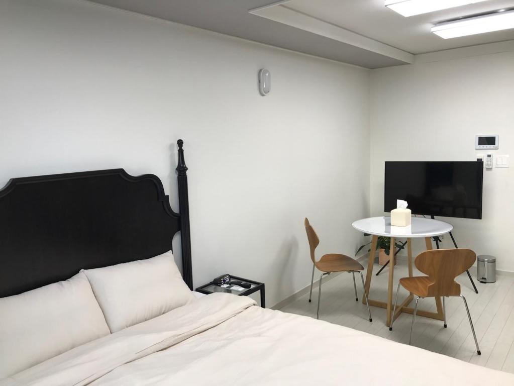 - une chambre avec un lit, une table et une télévision dans l'établissement Gurujam, à Daegu