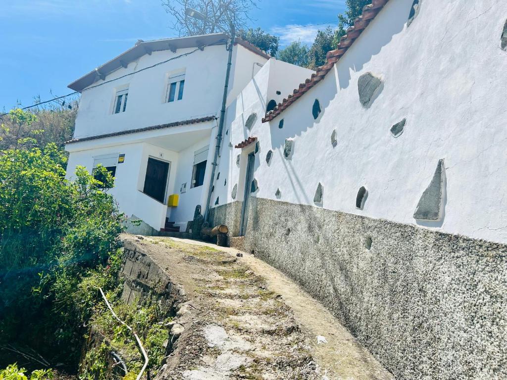 um edifício branco ao lado de uma parede de pedra em Garancor em Valleseco