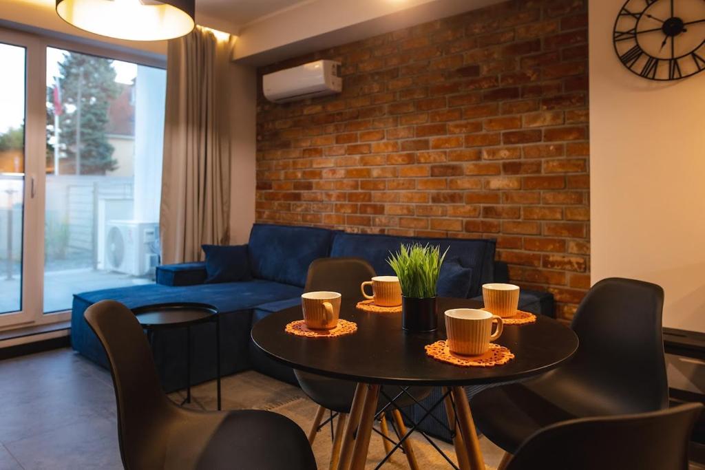 - un salon avec une table, des chaises et un canapé bleu dans l'établissement Apartament Loft Mazury, à Węgorzewo