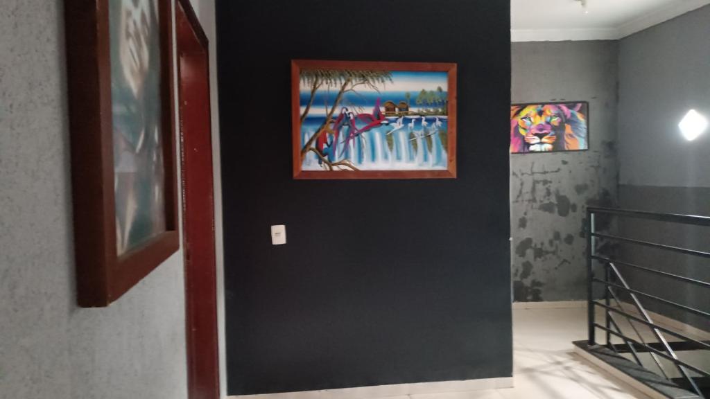 a hallway with two paintings on a black wall at Casa em rio verde in Rio Verde