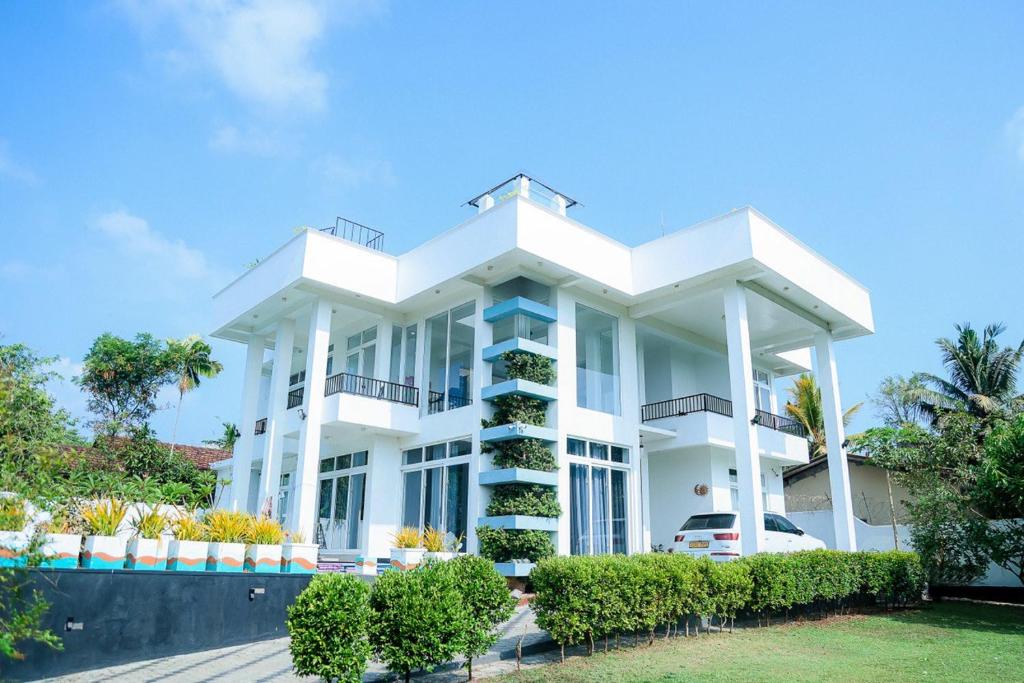 Bandaragama的住宿－Villa Water View，前面有灌木丛的白色大建筑