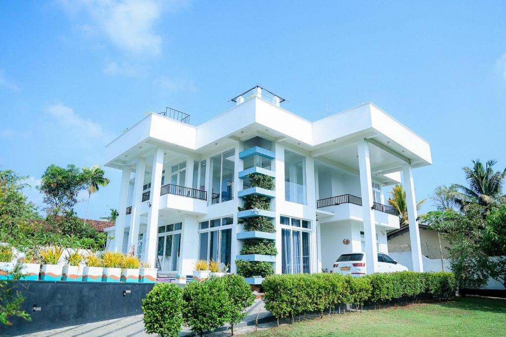 a large white building with bushes in front of it at Villa Water View in Bandaragama