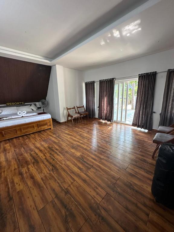 Habitación vacía con cama y suelo de madera. en Moon Light Resorts, en Ammāpettai