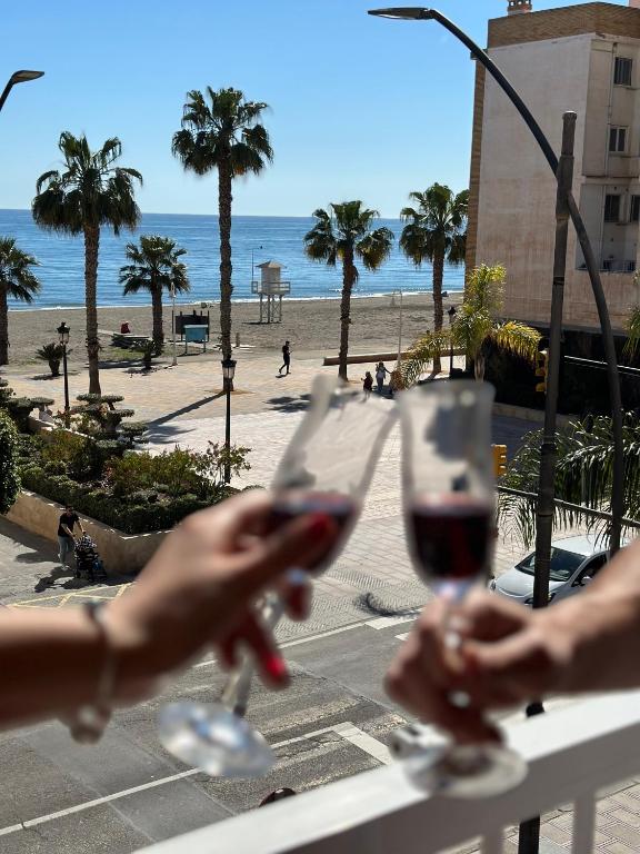 a person holding a glass of wine in front of the beach at Nonna Beach Apartment Two-Bedroom Sea Views 50 m from the Beach Wifi in Rincón de la Victoria