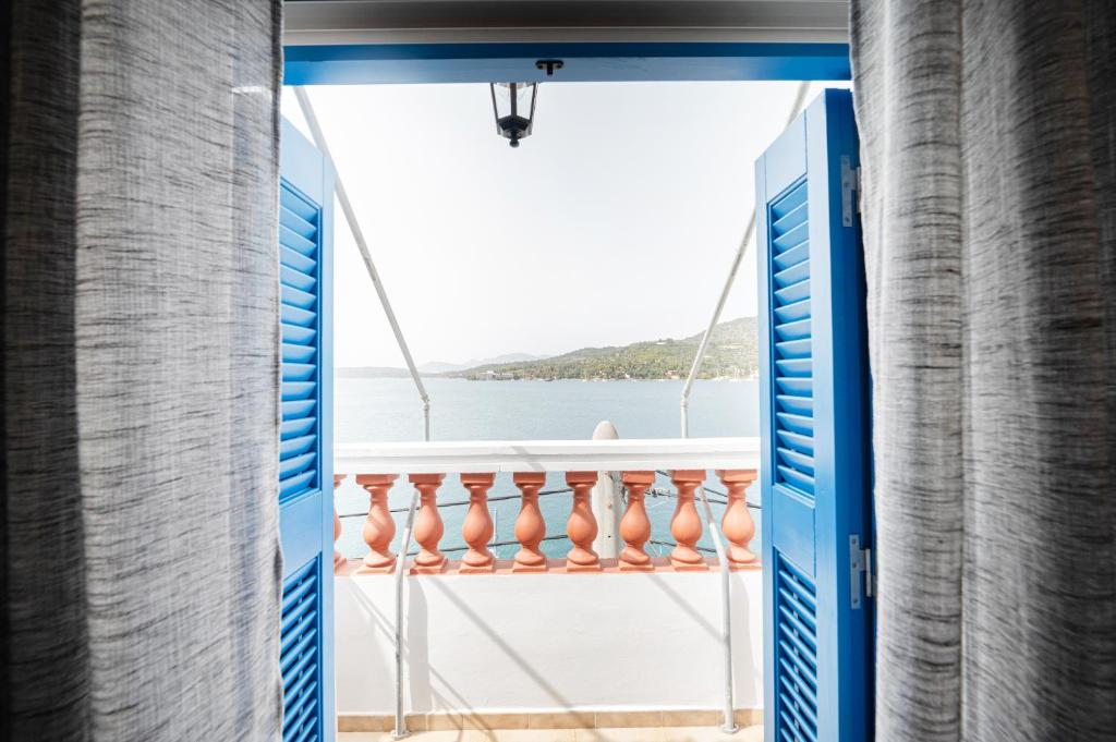 a room with a view of the ocean from a balcony at XENIOS APARTMENTS in Poros