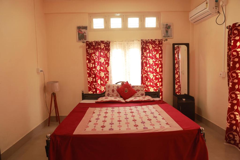 Schlafzimmer mit einem Bett mit roten Vorhängen und einem Fenster in der Unterkunft Cozy Haven in Jorhat