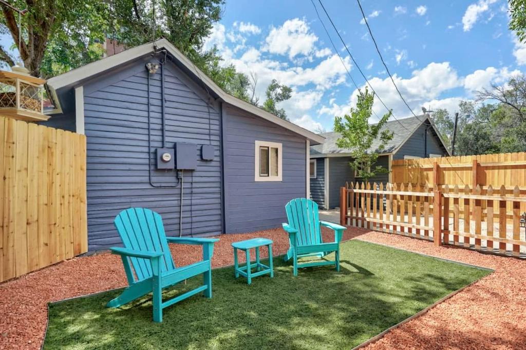 a yard with two blue chairs and a fence at Charming Half Pint Downtown Stay Pet Friendly in Colorado Springs
