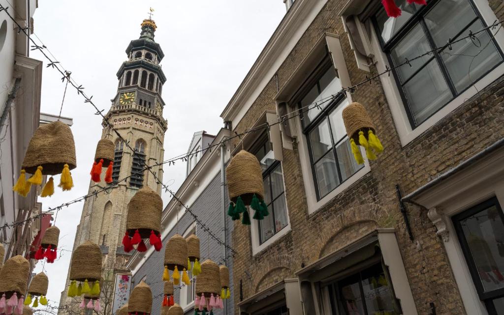 uma rua com cestas e uma torre de relógio ao fundo em B&B De zilveren reiger em Middelburg