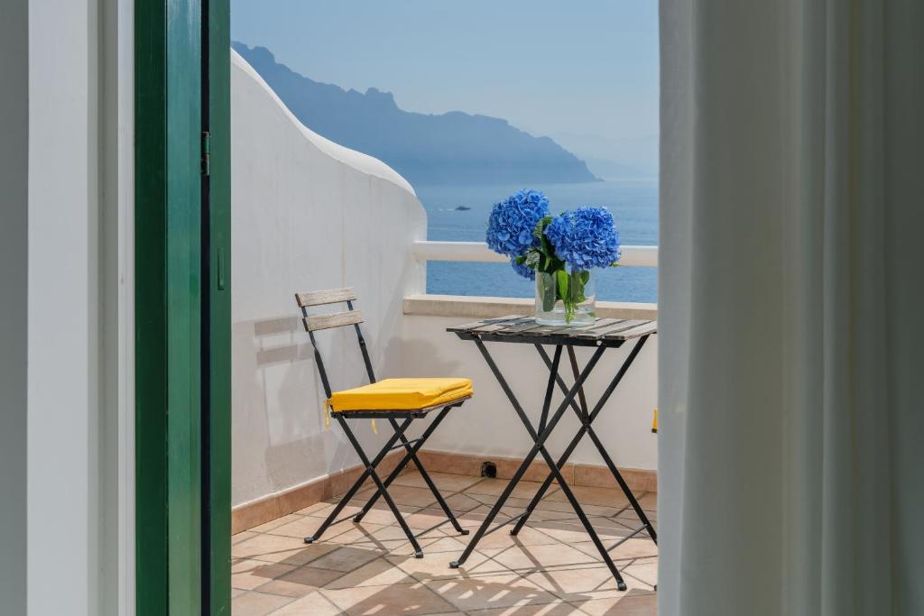 a table and chairs with a vase of flowers on a balcony at Hotel Le Terrazze in Conca dei Marini