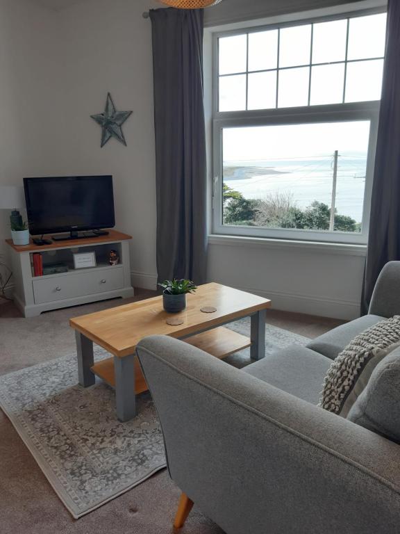 a living room with a couch and a table and a window at Seasalt Loft in Barmouth