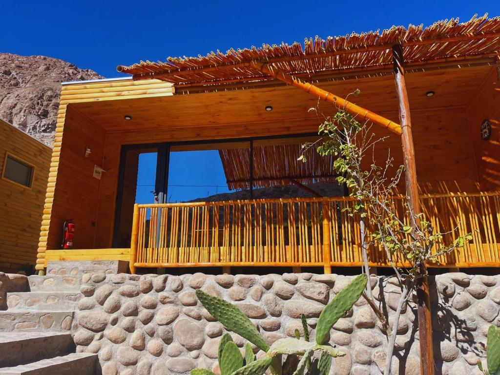 uma casa de madeira com uma parede de pedra em frente em Lodge El Pedregan em Codpa