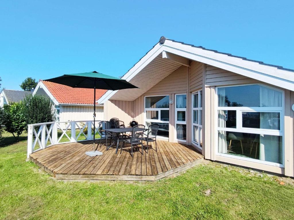 a wooden deck with a table and an umbrella at 4 person holiday home in Gelting in Gelting
