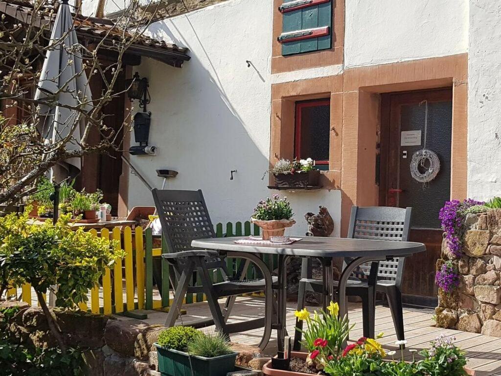 um pátio com uma mesa e cadeiras num quintal em Holiday apartment on Breitenberg em Wilgartswiesen