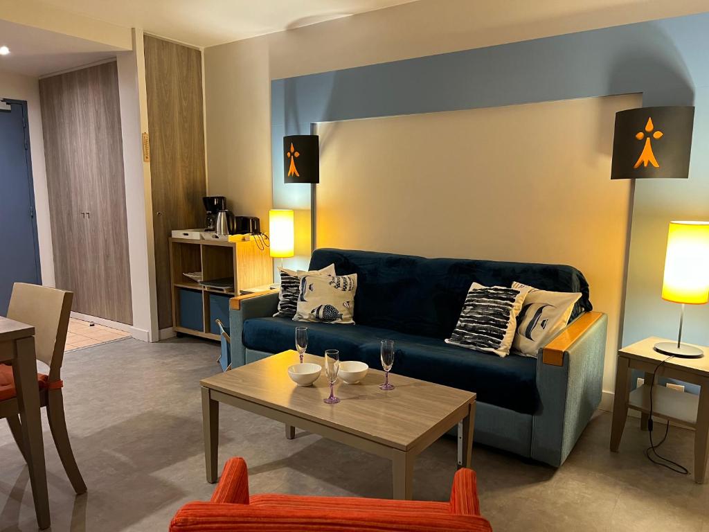 a living room with a blue couch and a table at DANS LES BRAS DE NEPTUNE - Plage de TRESTRAOU - Piscine - 4 à 5 personnes in Perros-Guirec