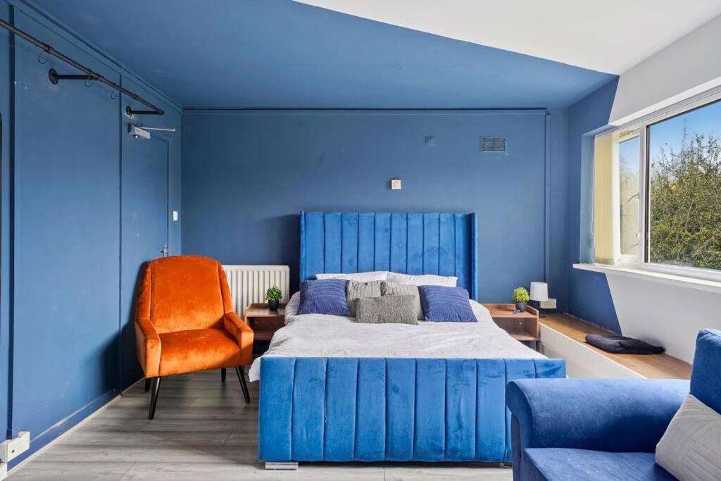 Dormitorio azul con cama y silla naranja en Cosy Retreat: Near Attractions & Comfortable!, en Birmingham
