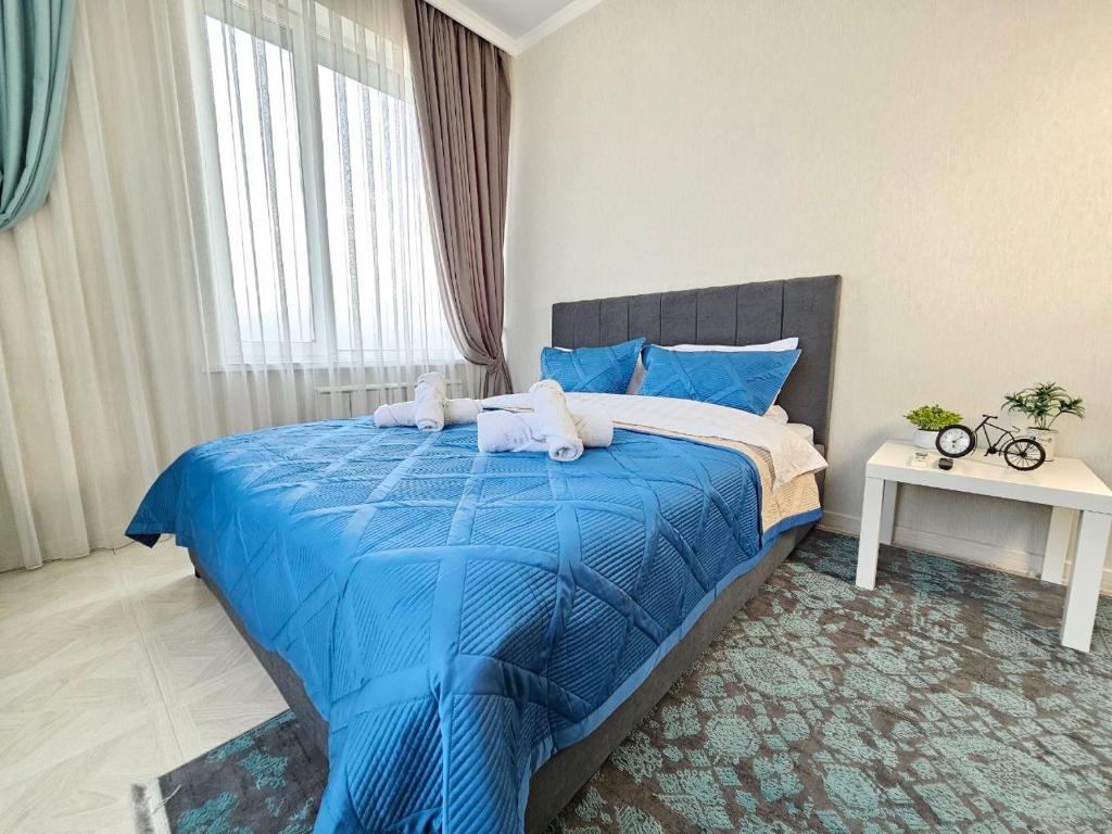 a bedroom with a blue bed with towels on it at ЖК ATREA 2 room Apartment in Almaty