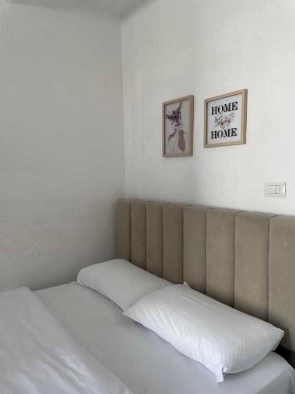 a bed with white sheets and two pictures on the wall at Rent rooms Loren in Vlorë