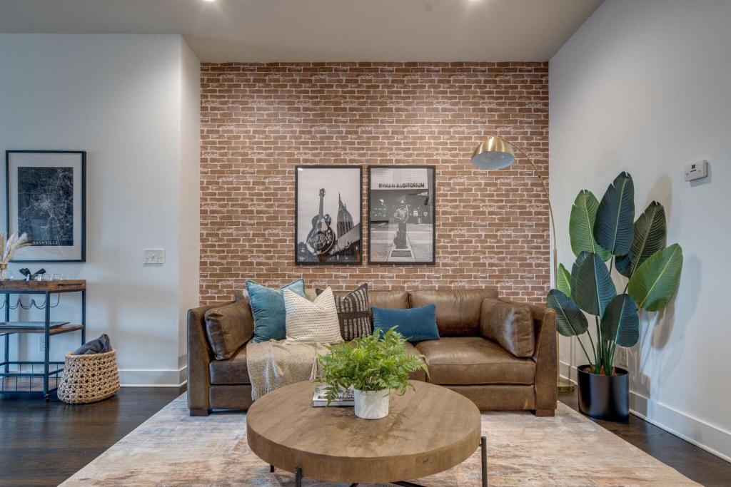 a living room with a couch and a brick wall at Lofts at 30th - 2 Top Floor Units in Nashville