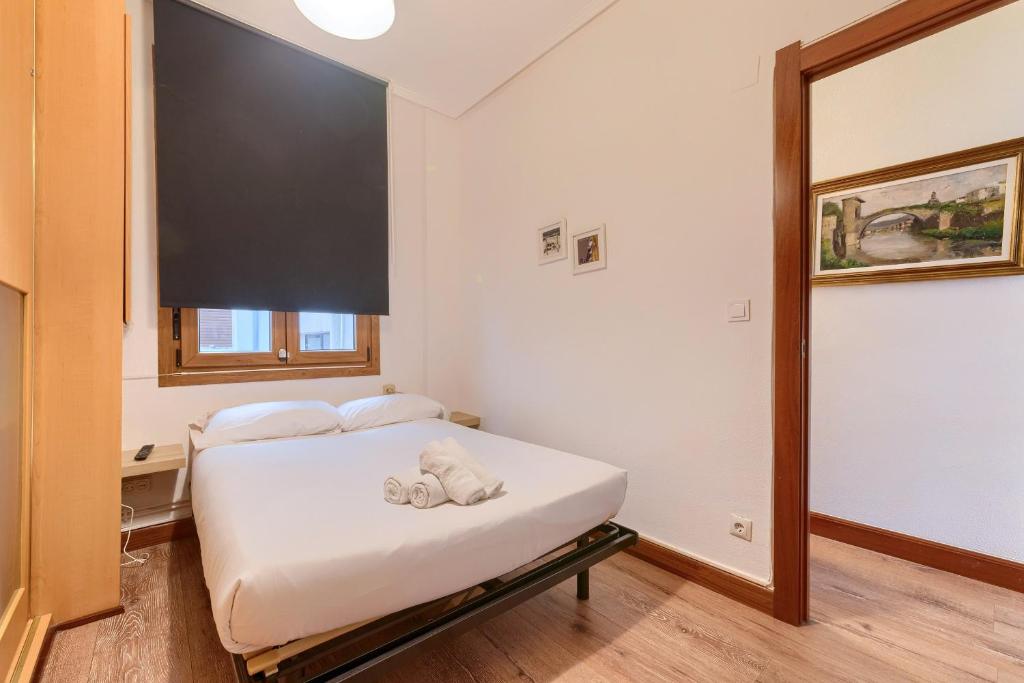 a bedroom with a white bed with a large screen at Vivienda Turística, Refugio Azkue Encanto y Comodidad in Bilbao
