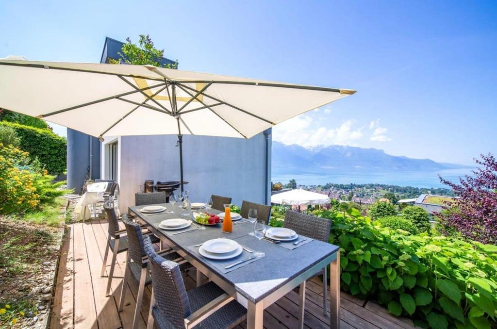 a dining table with an umbrella on a patio at Panoramic 3BD Dream Family Villa in Montreux by GuestLee in Le Châtelard-Montreux