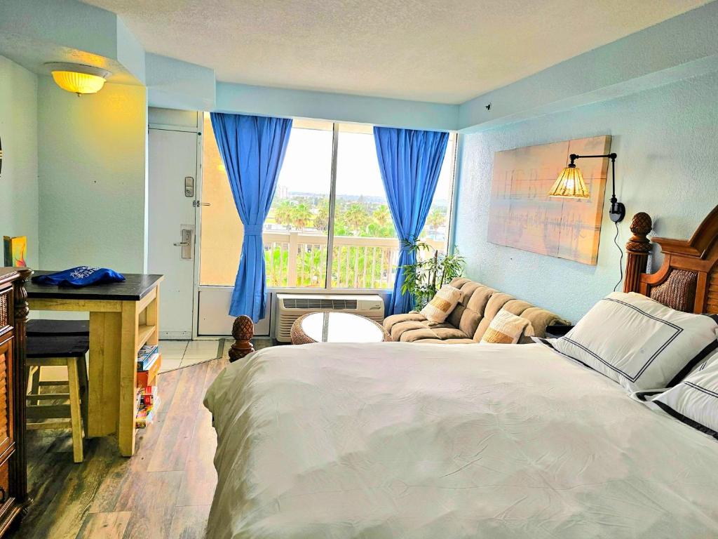 a bedroom with a bed and a couch and a window at Stay ON the beach! Wonderful location! in Daytona Beach
