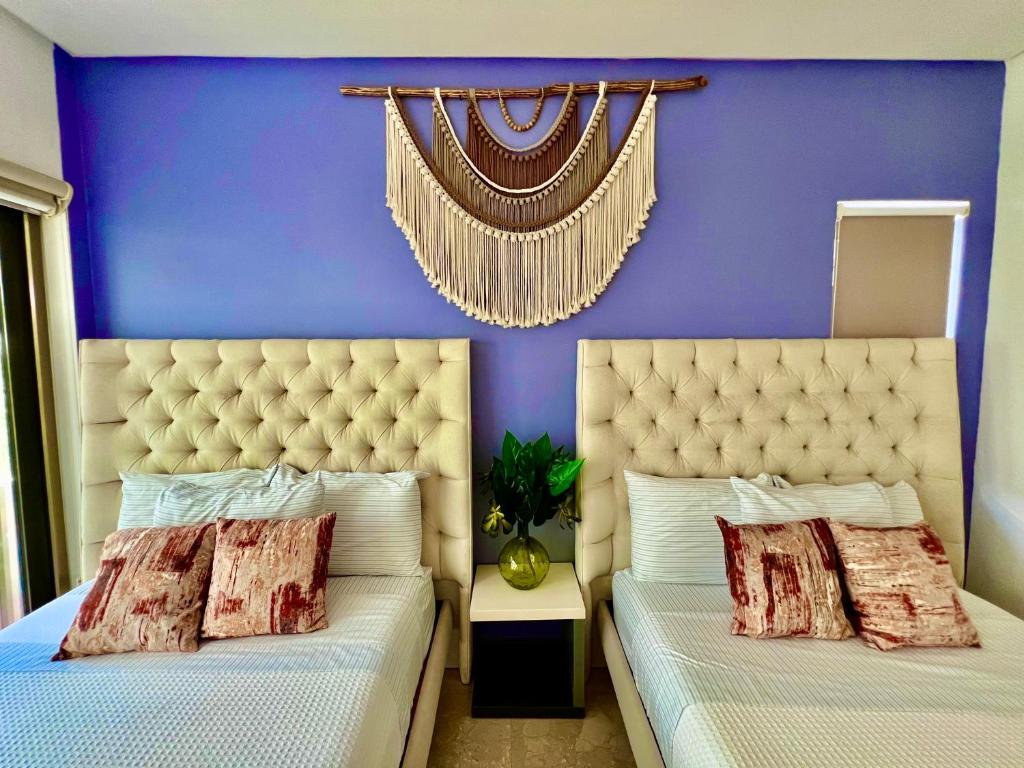 two beds in a bedroom with a purple wall at Spacious Penthouse w/ Private Pool & Maid Service in Puerto Morelos