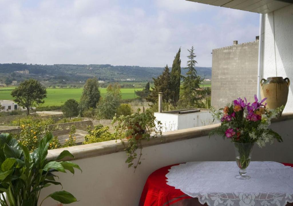 a table with flowers on a balcony with a view at B&B Vigna La Corte in Alessano
