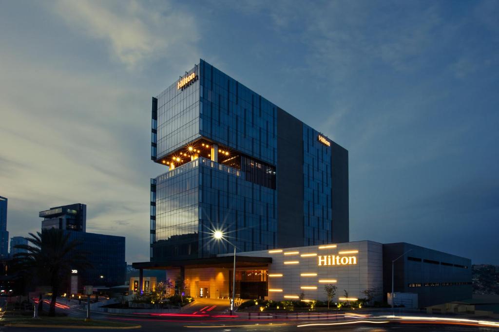 Un grand bâtiment avec des lumières devant lui dans l'établissement Hilton Monterrey, à Monterrey