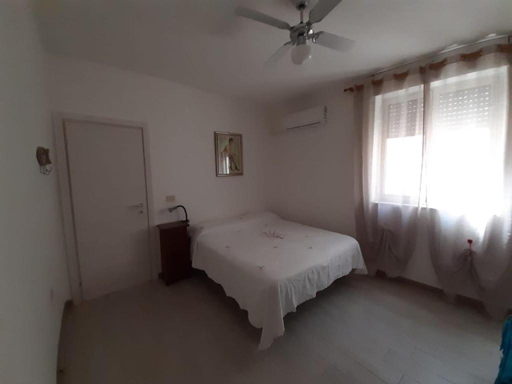 een witte slaapkamer met een bed en een raam bij Casa Greta in Iglesias