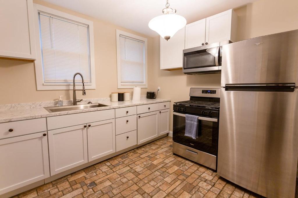 La cuisine est équipée de placards blancs et d'un réfrigérateur en acier inoxydable. dans l'établissement New Listing - 1 Bed House experienced super host, à Bellevue