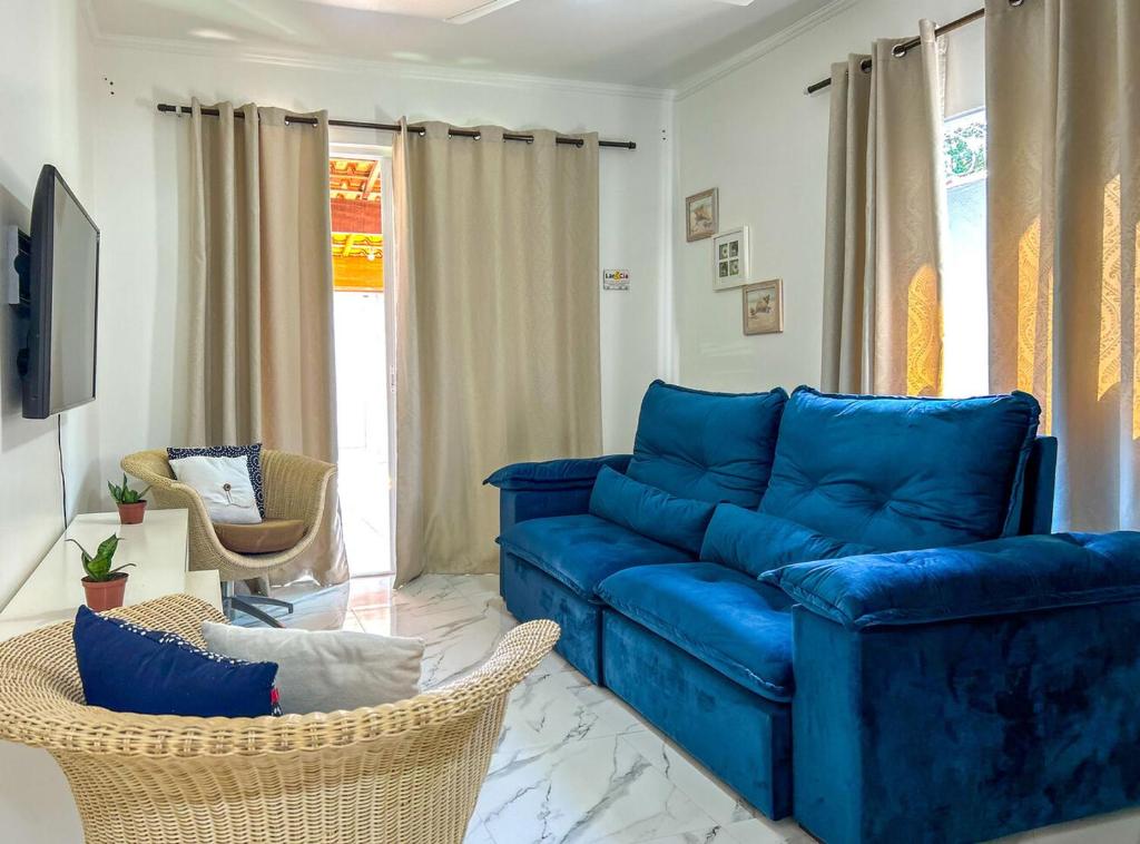 een woonkamer met een blauwe bank en stoelen bij Casa c otima localizacao e Wi-Fi em Bertioga SP in Bertioga