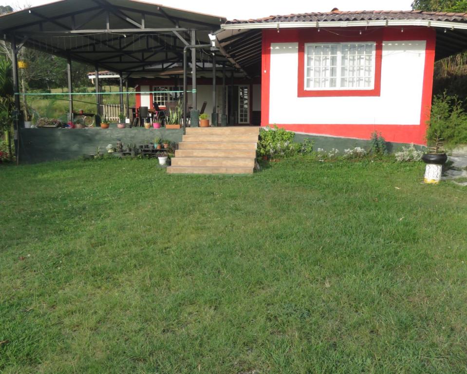 a red and white house with a grass yard at HOTEL PURA VIDA in Santa Rosa de Cabal