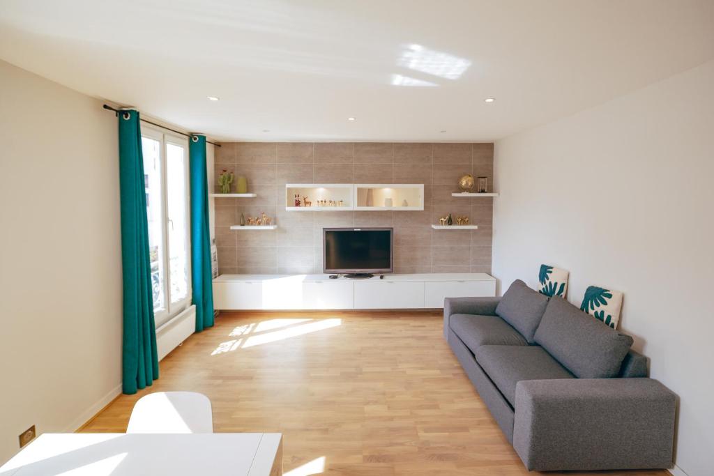 un salon avec un canapé et une télévision dans l'établissement Paris15em Charles Michels Appartement, à Paris