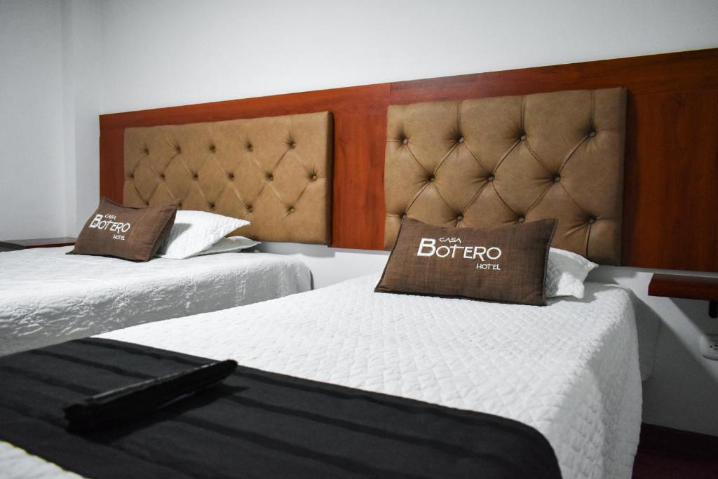 two beds in a hotel room with a sign on them at Hotel Casa Botero 205 in Bogotá