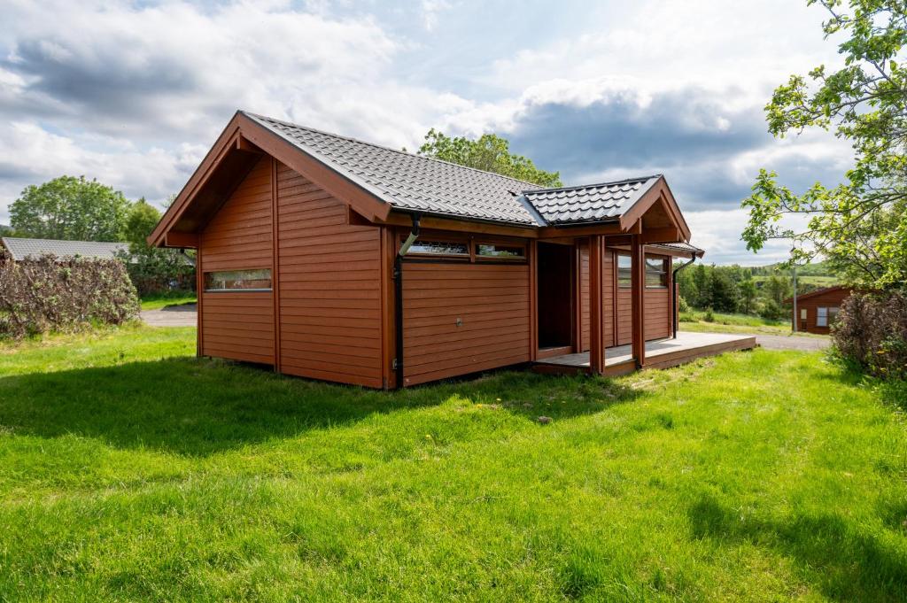 a small cabin with a roof on a grass field at Gladheimar Cottages in Blönduós