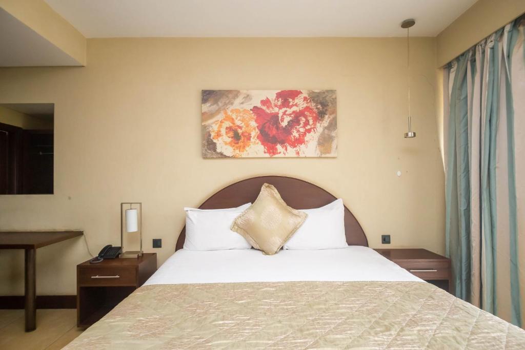 a bedroom with a bed and a painting on the wall at Taarifa Suites by Dunhill Serviced Apartments in Nairobi