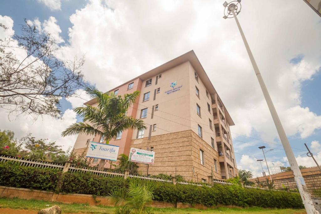 een gebouw met een palmboom ervoor bij Taarifa Suites by Dunhill Serviced Apartments in Nairobi