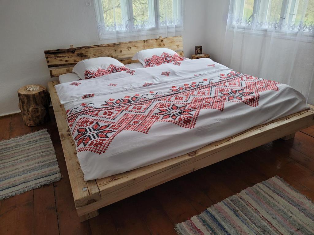 a bed with a red and white blanket on it at Casa Izvorul Rece in Cîmpeni