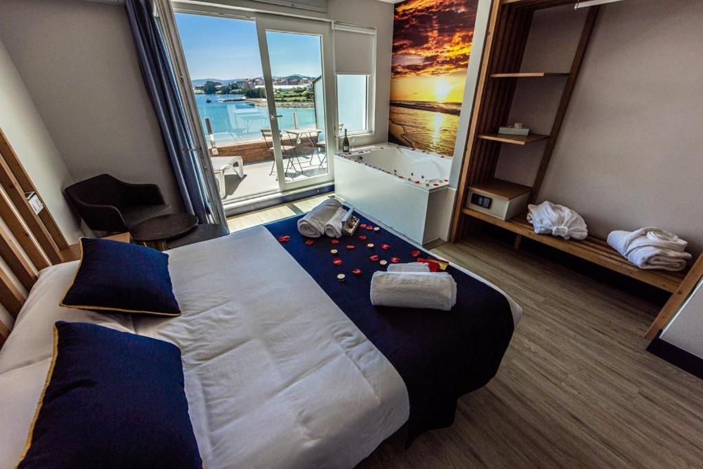 a hotel room with a large bed and a large window at Playa de Camariñas in Camariñas