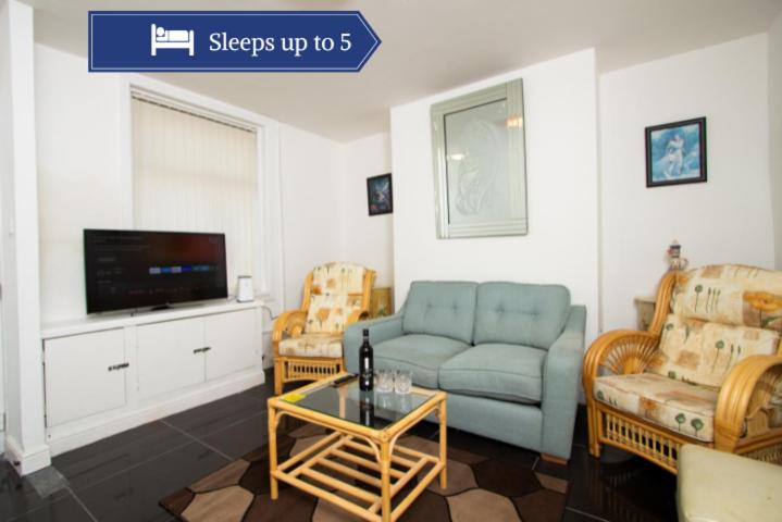 uma sala de estar com um sofá e uma televisão em Metropolitan Charm: Stylish 2BR House em Manchester