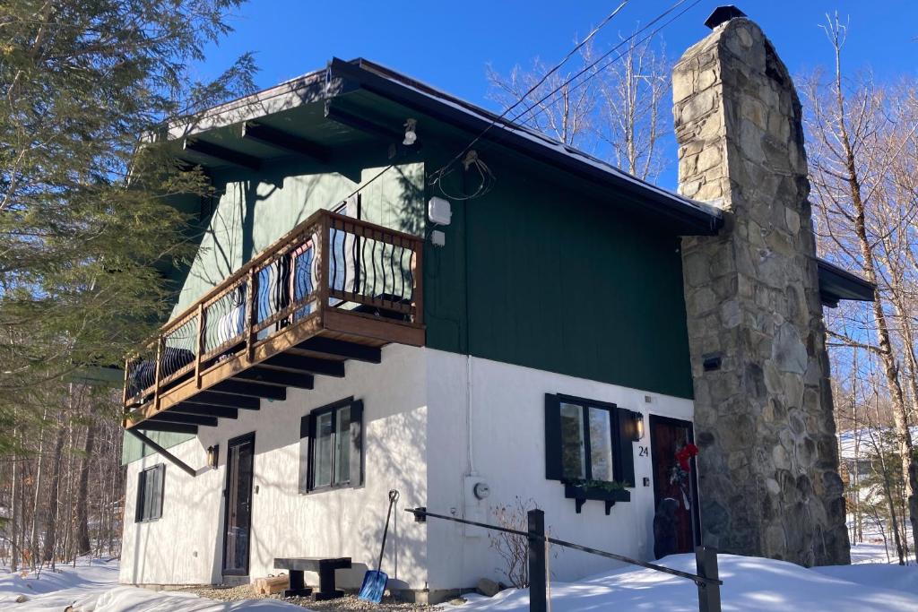 ein grün-weißes Gebäude mit Balkon in der Unterkunft Wandering Creek Ski Lodge in Stratton Mountain